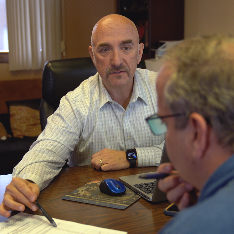 Business professional having a focused discussion with a client at a desk, reviewing documents and financial details to provide tailored accounting advice.